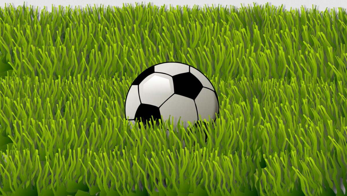 Fußball im tiefen grünen künstlichen Rasen.